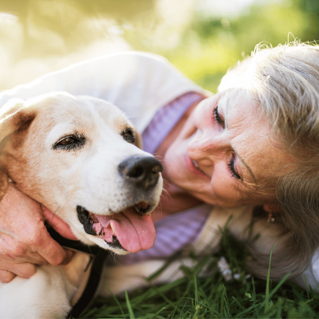 a woman lying on grass with a dog