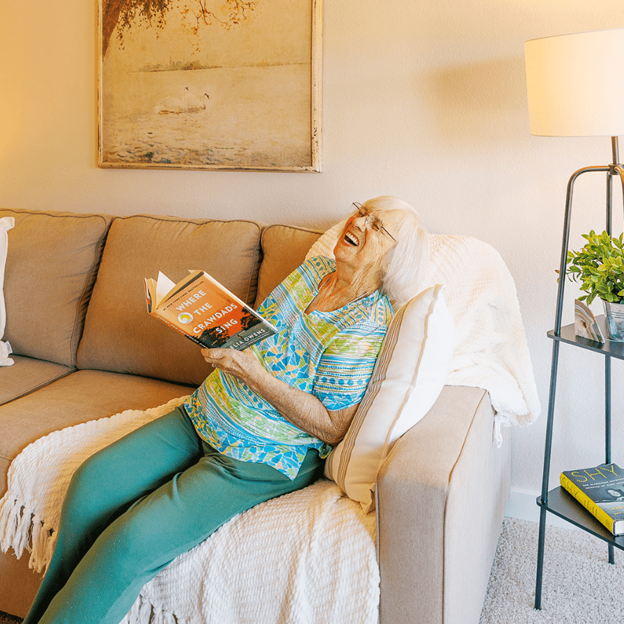a woman sitting on a couch reading a book