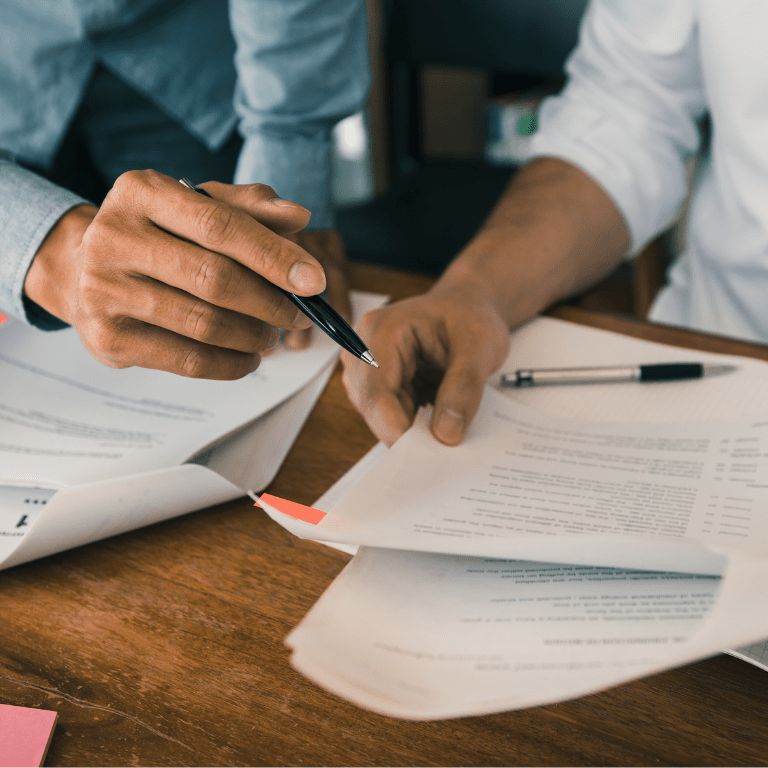 a person holding a pen over papers