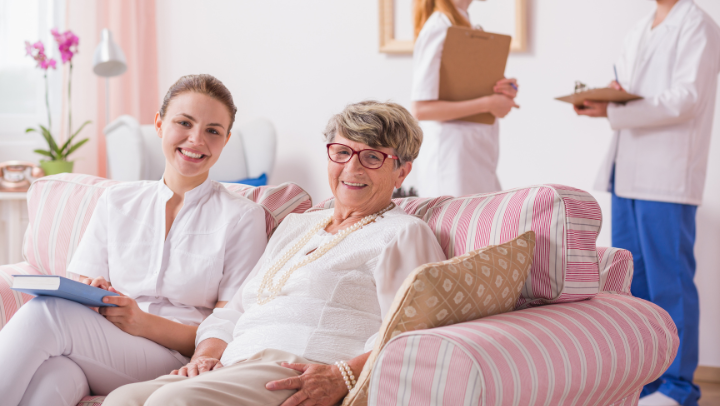 an old lay with a nurse in a sofa. 
